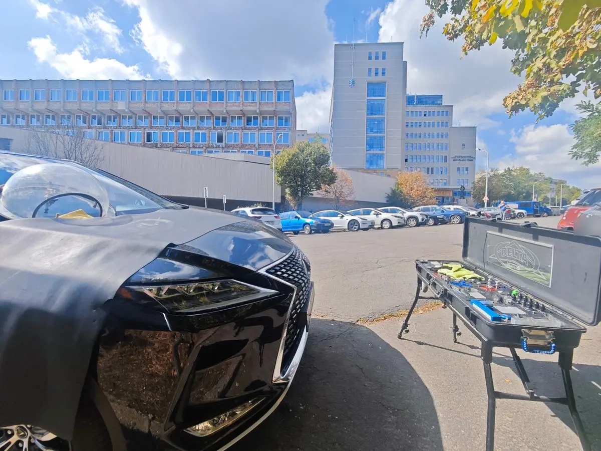Szélvédő javítás a XII. kerületben, a Kútvölgyi tömb melletti parkolóban – a szélvédőn UV-védő búra, mellette a Delta Kits szerszámkészlet