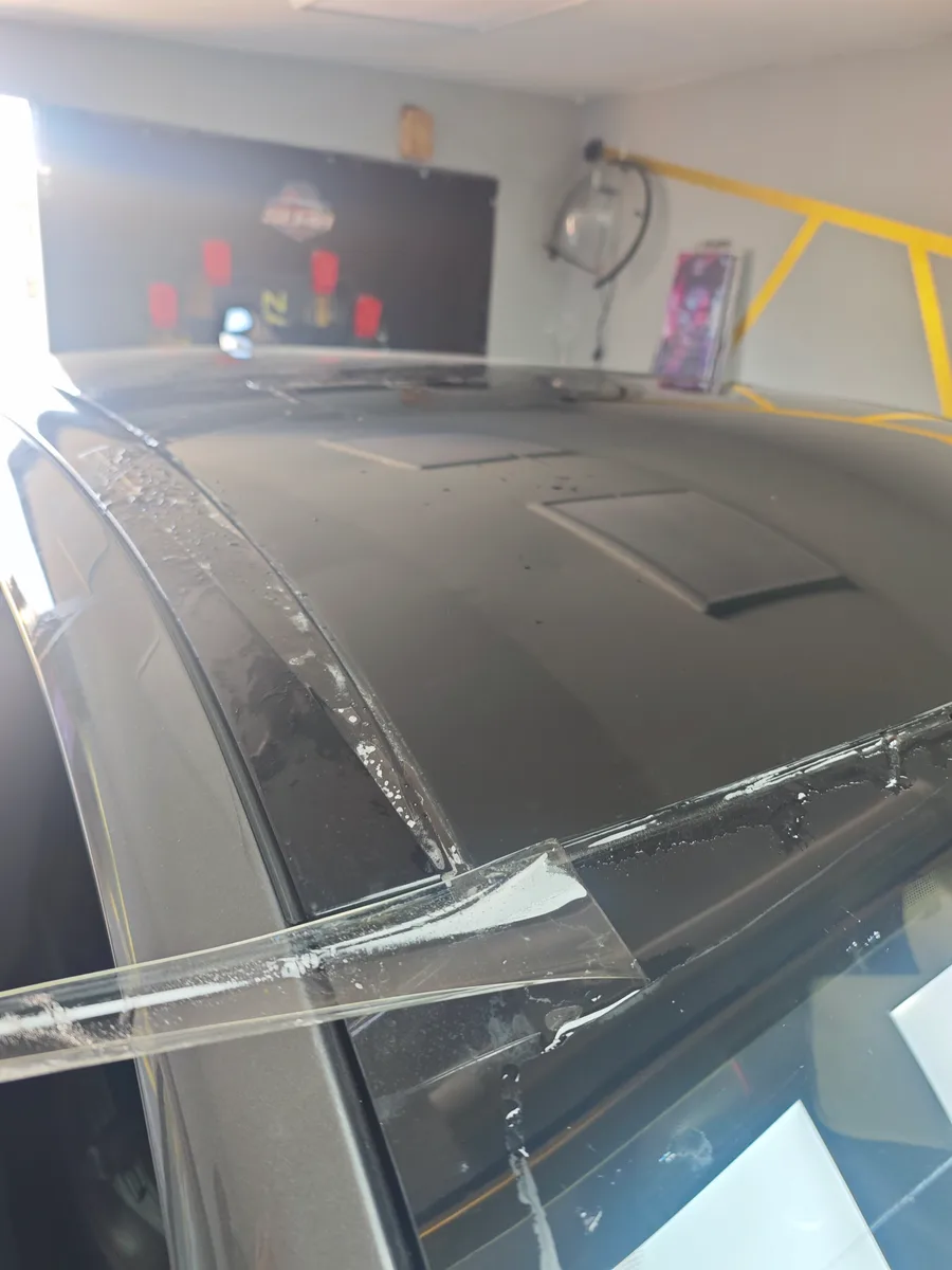 Kővédő fólia illesztése egy Ford Mustang Mach-E panorámatetőjének élén, közelről